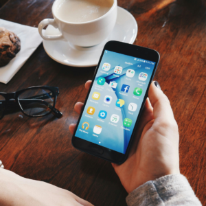 A woman is holding up her phone, where we can see social media apps.